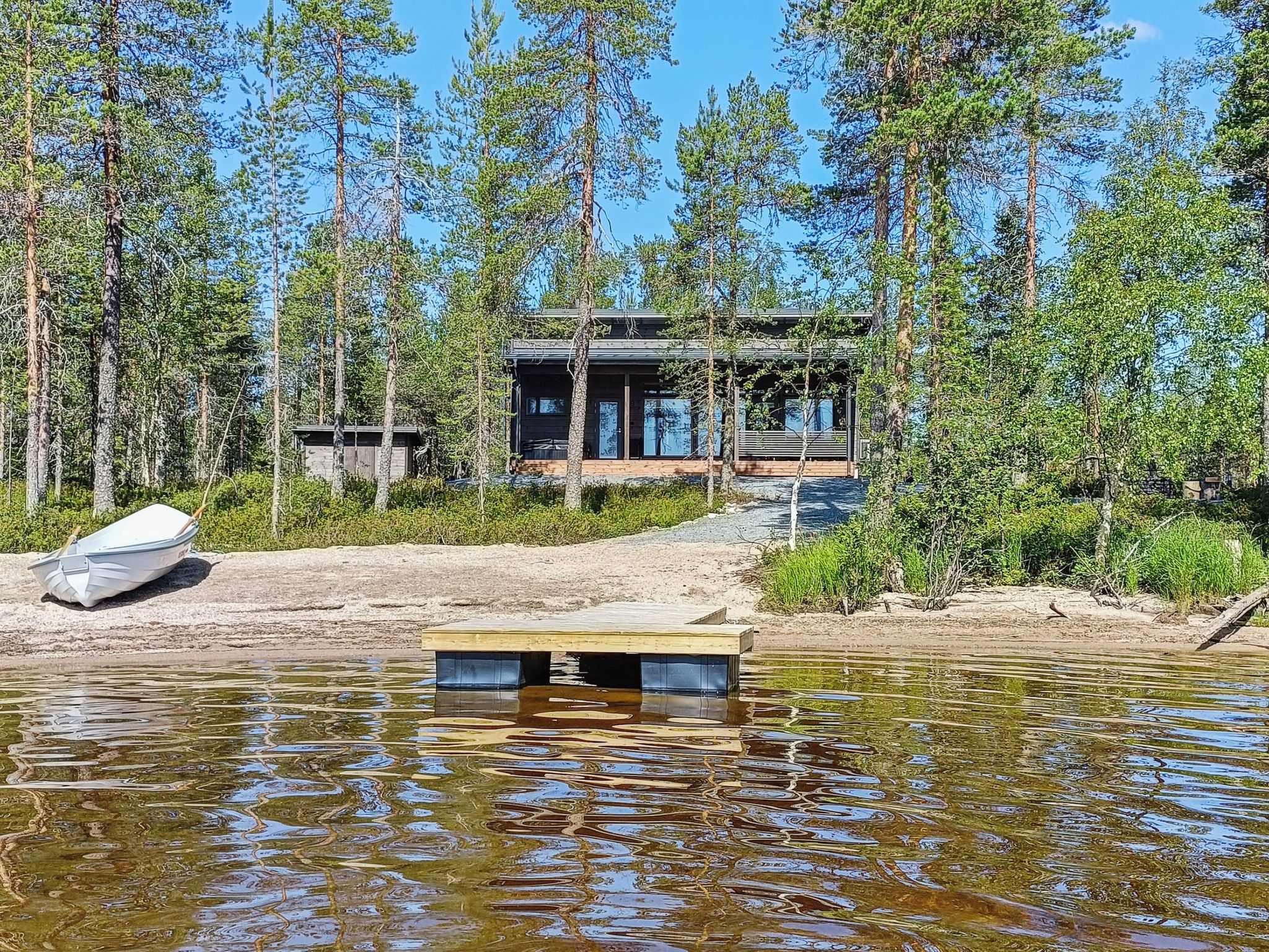 A cabin with a dock extending into a lake, surrounded by dense forest.