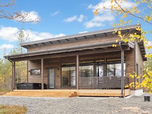 Een modern houten chalet met een overdekte veranda, grote ramen en een houten terras.