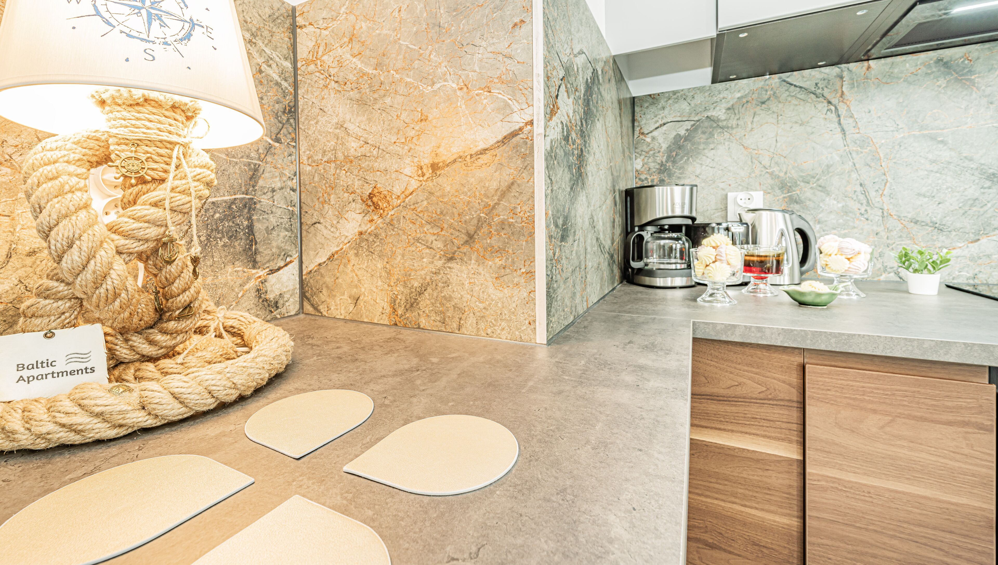 A kitchen with a marble backsplash, a coffee maker, and a lamp with a rope base.