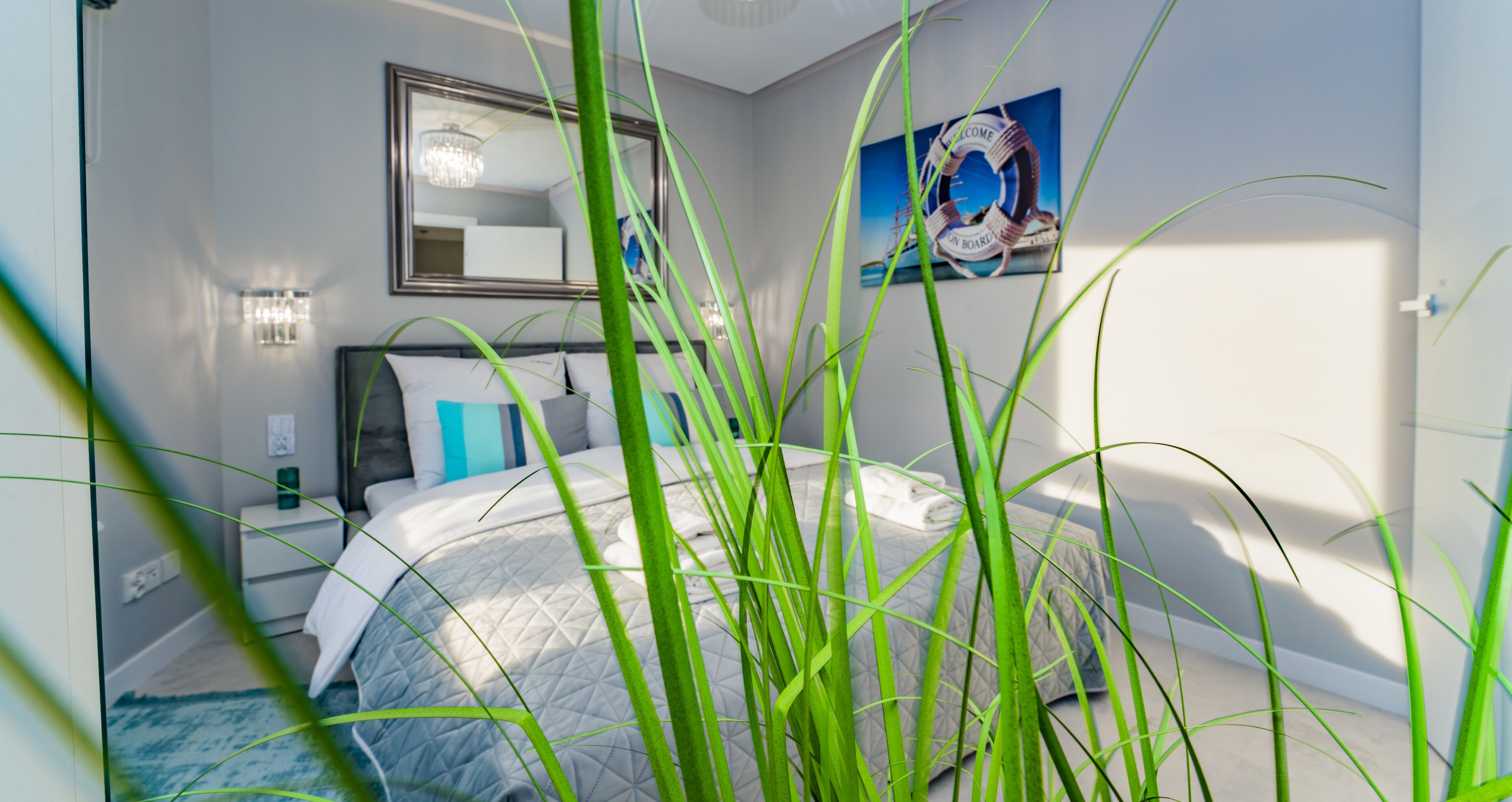 Une chambre à coucher avec un lit, des lampes de chevet, un miroir et un panneau d’accueil sur le mur.