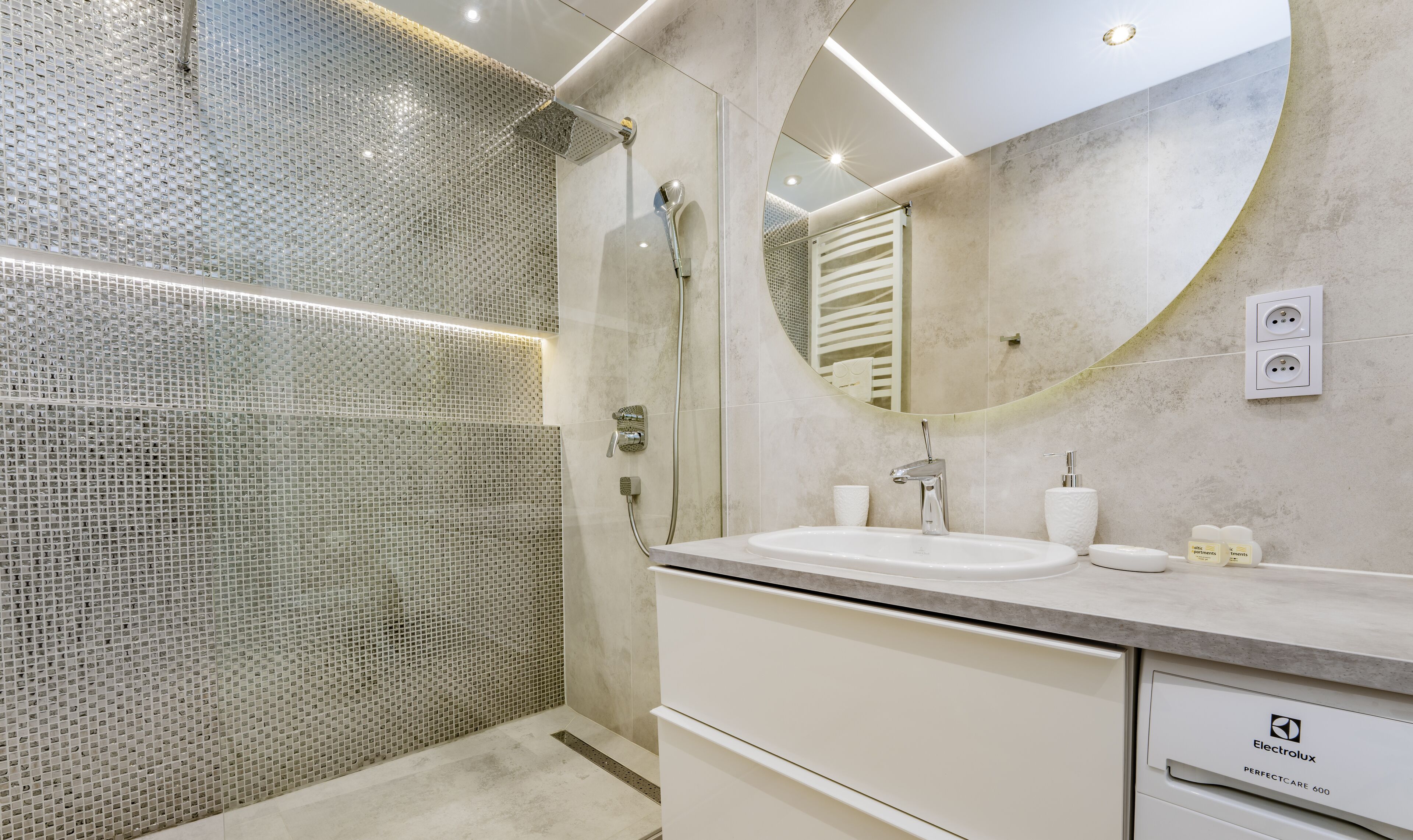 A modern bathroom with a glass shower enclosure, a large mirror, and a white sink with a countertop.