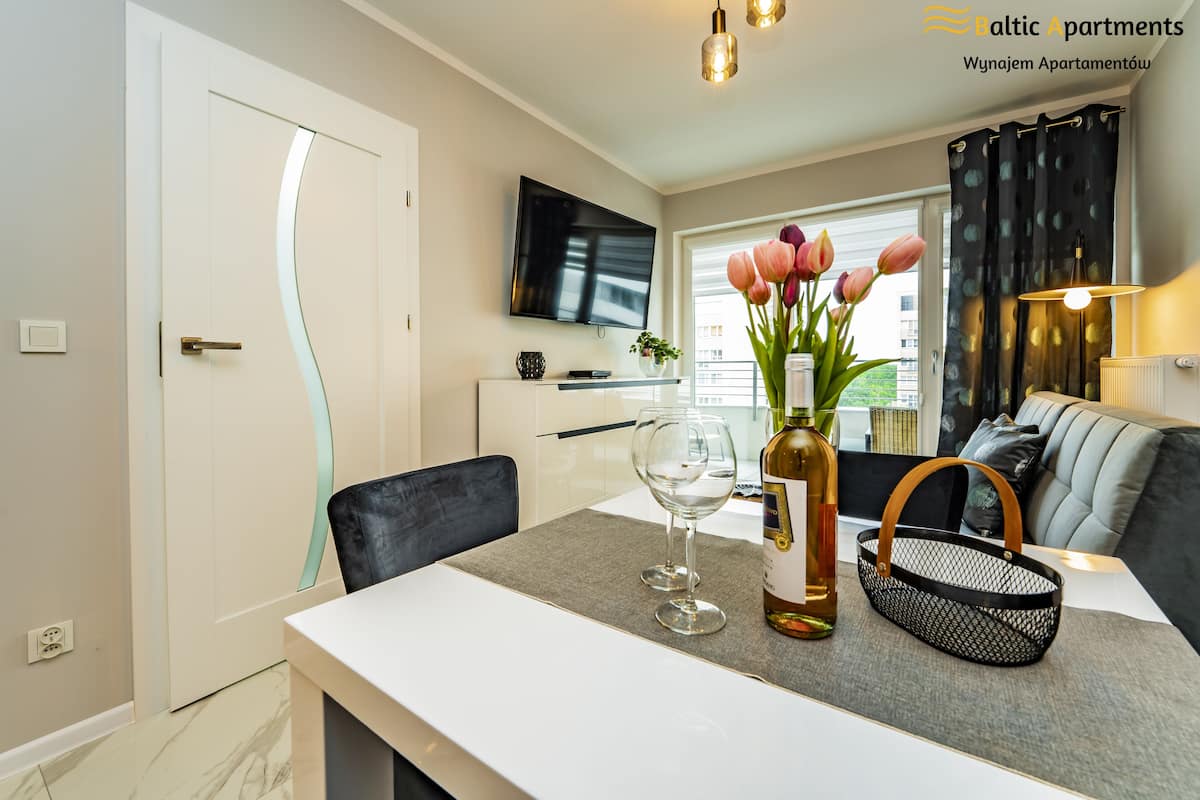 Een moderne woonkamer met een eethoek, een flatscreen televisie en een raam met gordijnen.