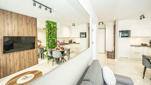 Een moderne keuken met witte kasten, een inbouwoven en een eethoek met een ronde tafel en stoelen.