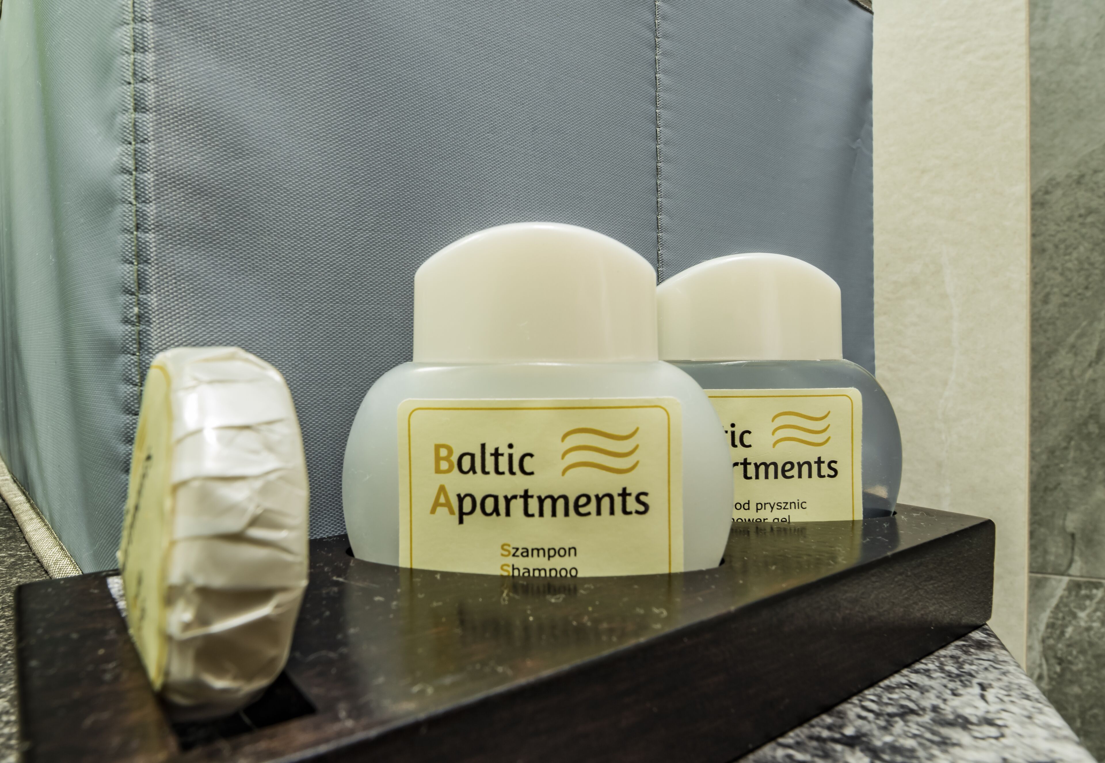 Uma bancada de banheiro com artigos de higiene pessoal, incluindo uma garrafa de shampoo e um sabonete.
