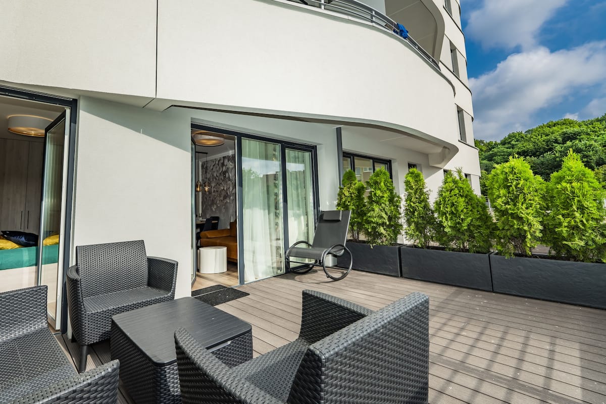 Een modern buiten zitgedeelte met rieten meubilair en een houten terras.