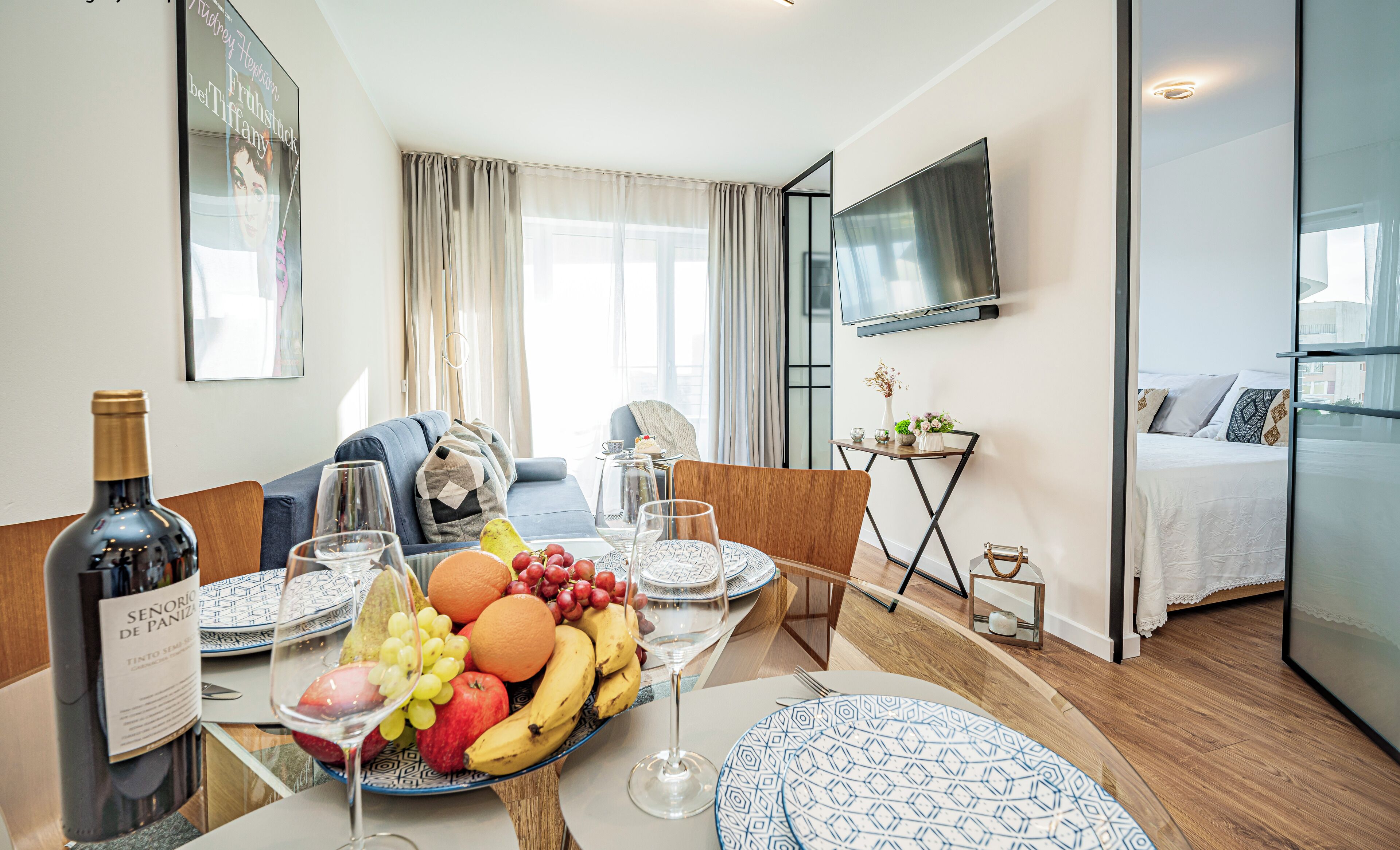Une chambre d’hôtel comprenant un coin repas, un lit, une télévision et une fenêtre avec des rideaux.
