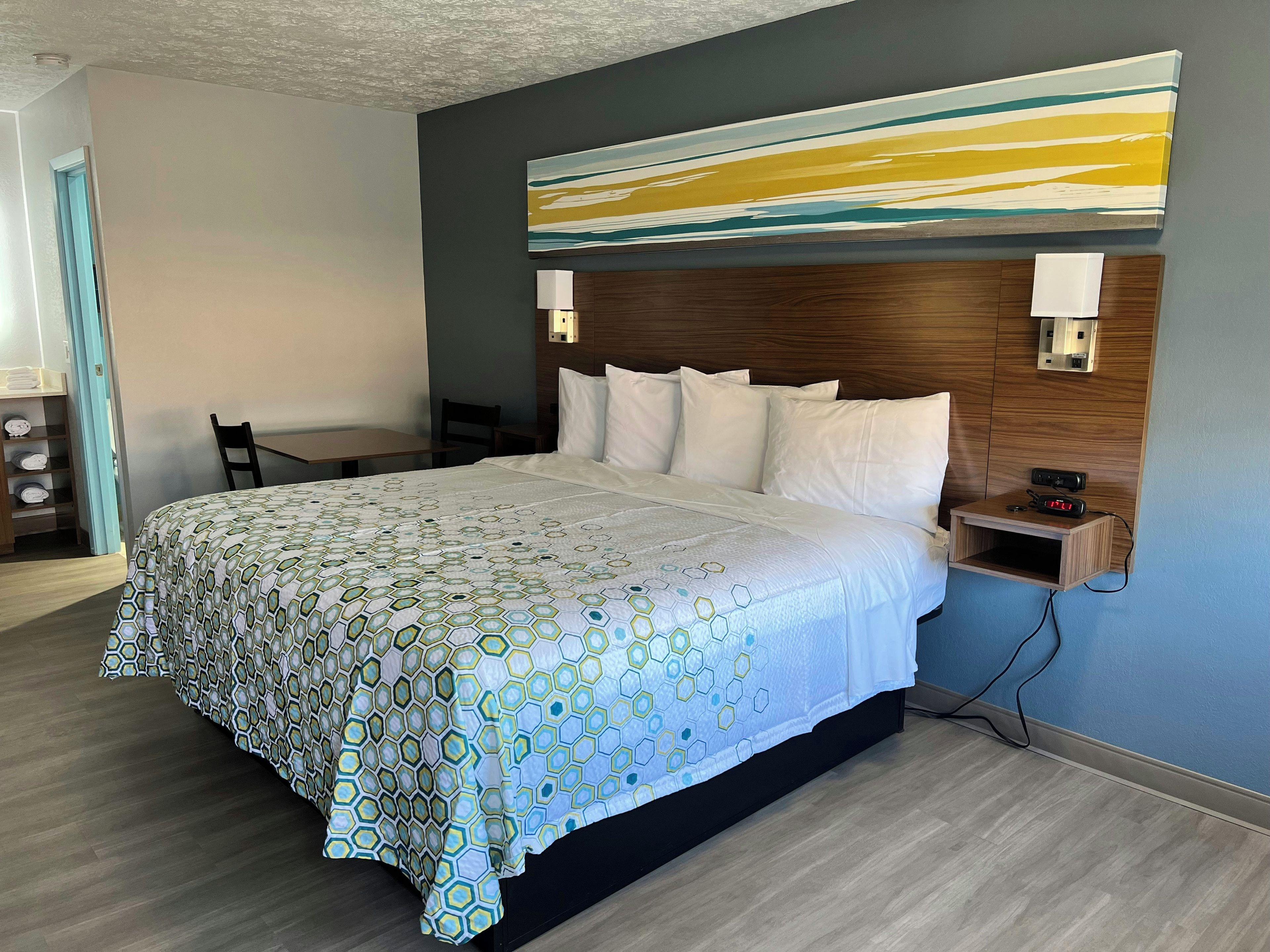 Una habitación de hotel con una cama grande, un cabecero de madera, un escritorio y una silla.