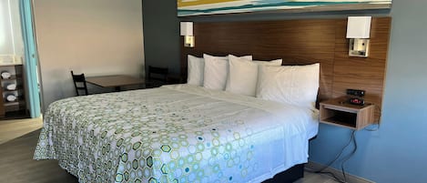 Une chambre d’hôtel avec un grand lit, une tête de lit en bois, un bureau et une chaise.