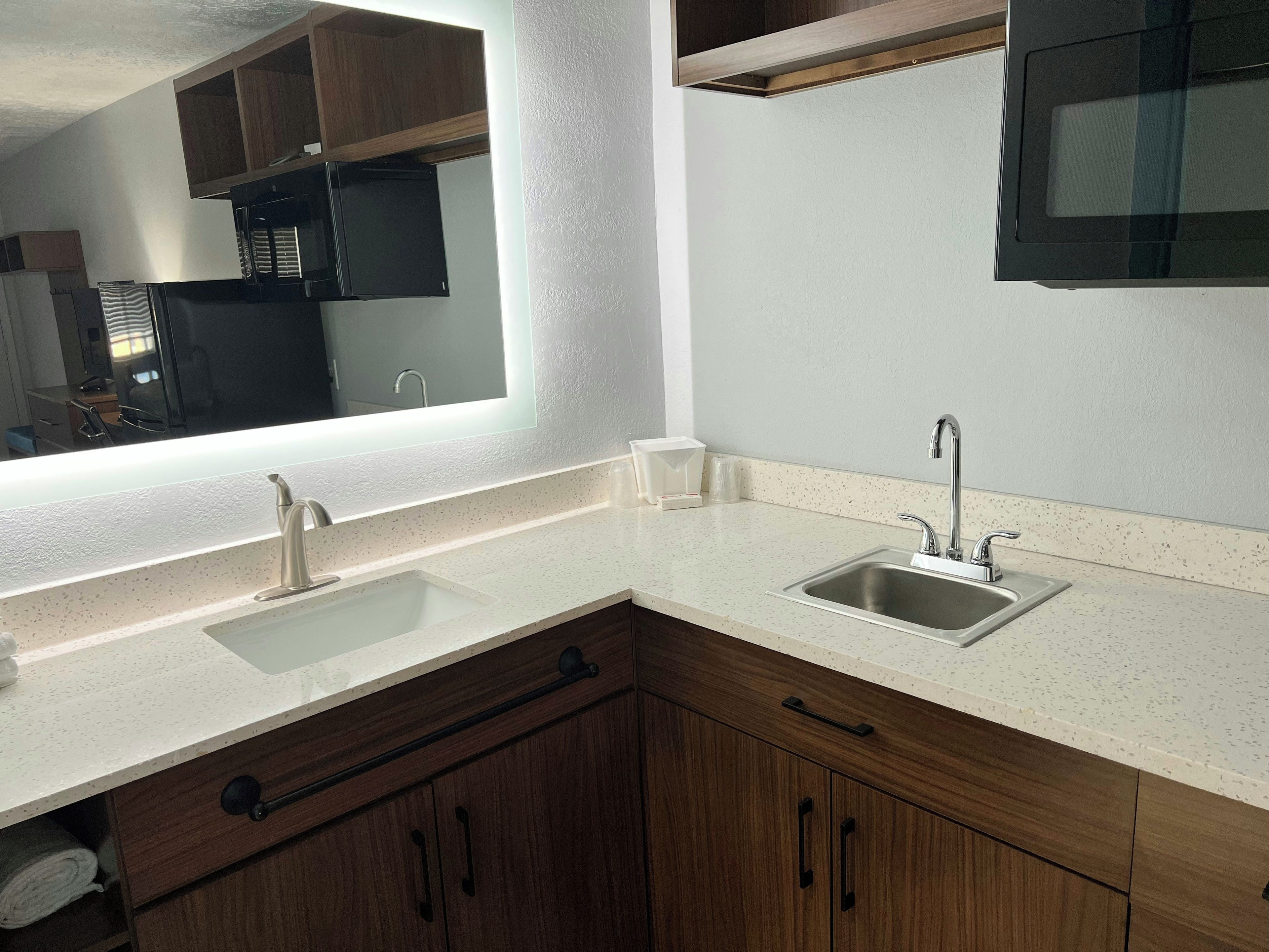 A kitchen with two sinks, wooden cabinets, and a large mirror.