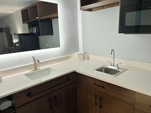 A kitchen with two sinks, wooden cabinets, and a large mirror. - HomeTowne Studios by Red Roof Georgetown, KY (Georgetown)