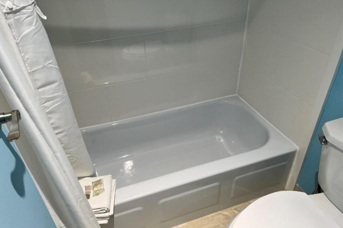 Bañera con ducha, toallas, jabón, shampoo