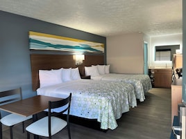 Habitación de hotel con una cama grande, un escritorio y una silla. Hay un cuadro en la pared y una ventana con persianas.