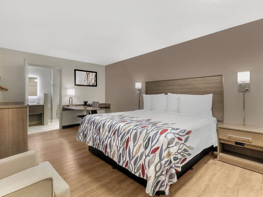 A hotel room with a bed, bedside tables, a desk, and a chair.