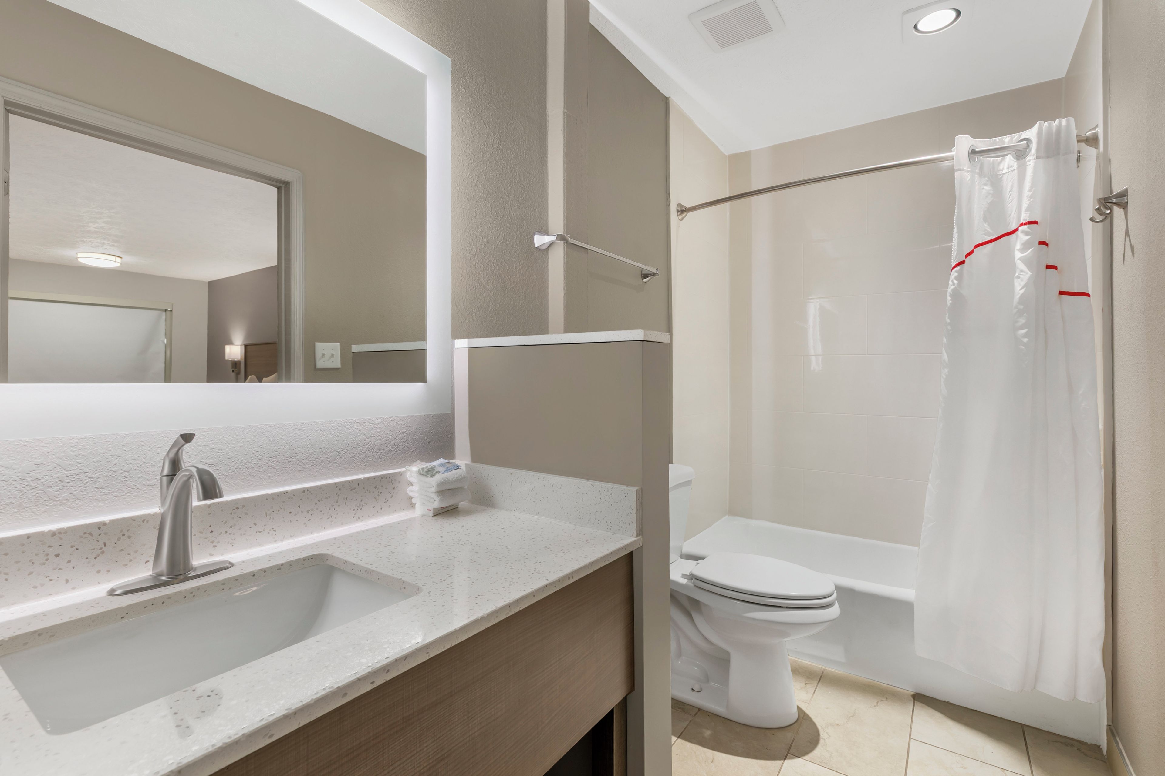 Une salle de bain moderne avec un lavabo, un miroir, des toilettes et une baignoire.