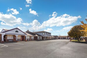 Une rangée de bâtiments d’un seul étage, avec un parking devant.