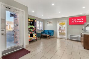 Un hall d’hôtel avec un distributeur automatique, un canapé bleu et un panneau indiquant que le Wi-Fi est disponible gratuitement.
