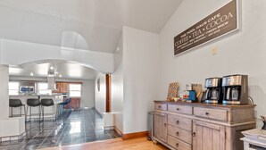 Uma cozinha moderna com área de bar, espaço para café e uma placa indicando uma cafeteria.