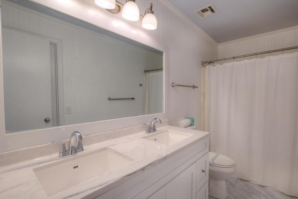 A bathroom with a double sink vanity, a large mirror, and a shower curtain.