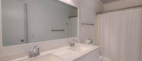 A bathroom with a double sink vanity, a large mirror, and a shower curtain.