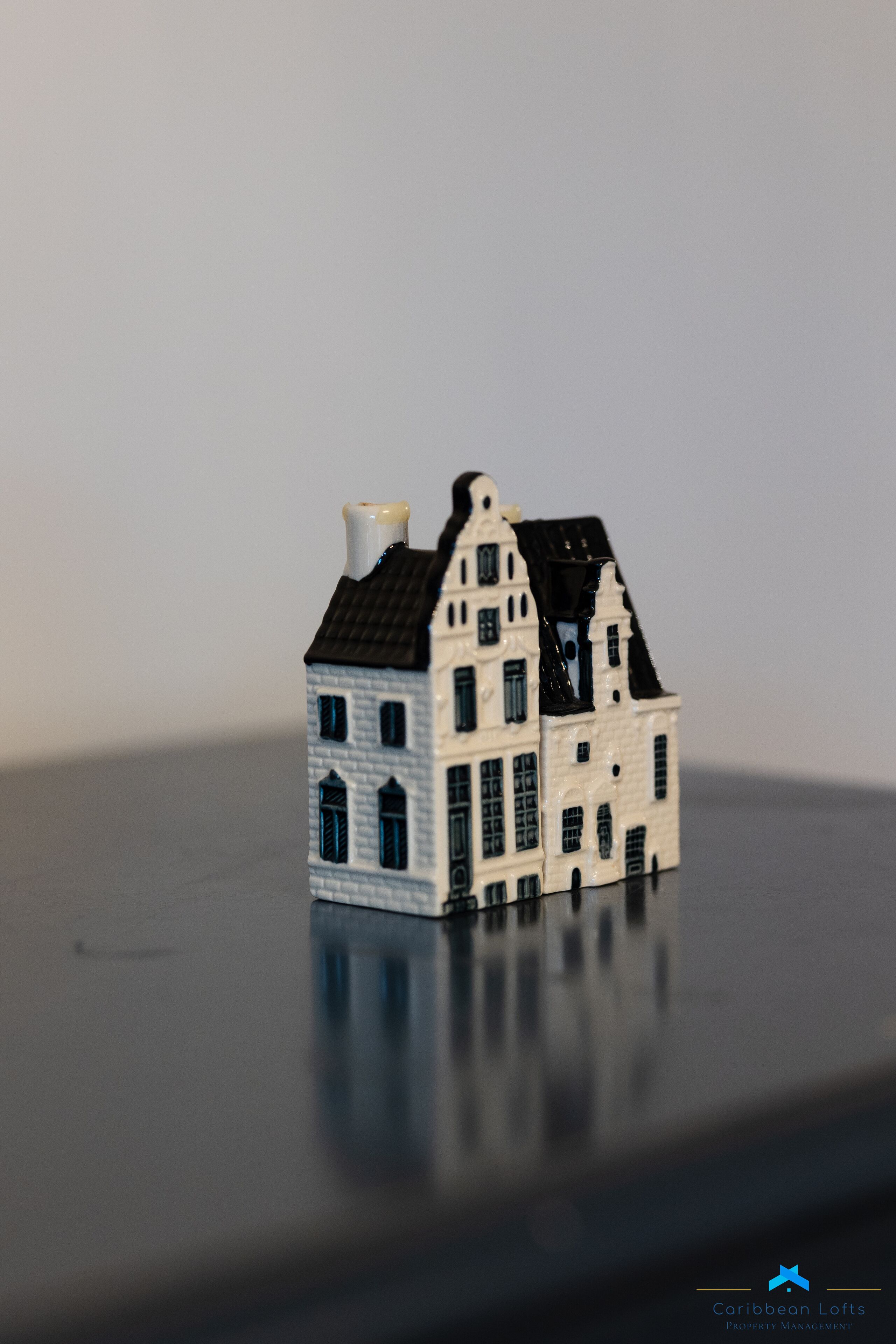 A miniature model of a two-story building with a steep roof and multiple windows.