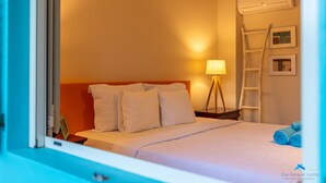 A hotel room with a bed, a nightstand, a lamp, an air conditioning unit, and a ladder. - Beautiful condo with sea view (Kralendijk)