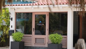 A building with a sign reading "Caribbean Lofts" and a door with a window. There are two potted plants in front of the door. - Beautiful condo with sea view (Kralendijk)