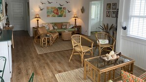 A cozy living room with a sofa, chairs, and a glass coffee table. - Coquina Cottage on Vilano Beach (St. Augustine)