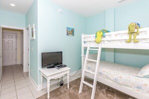A room with a bunk bed, a desk with a computer, and a door.