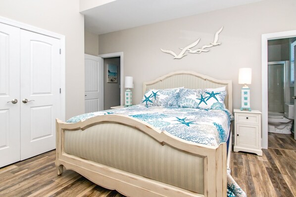 A bedroom with a bed, a nightstand, a wall-mounted light, and a door.