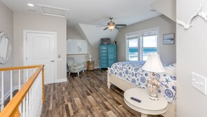 A bedroom with a bed, a ceiling fan, a dresser, a chair, and a view of the ocean. - Pier Pressure - Amazing Oceanfront 6 BR Half Duplex; Hot Tub and more! Pet (Surf City)