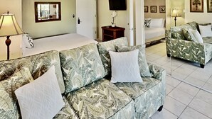 Quarto de hotel com cama, sofá, televisão e porta.