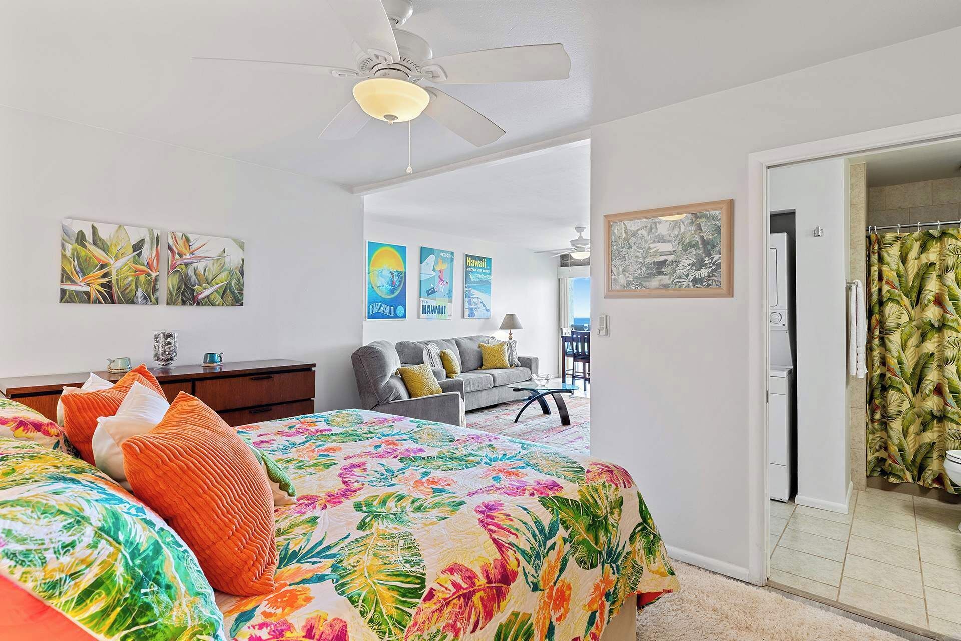 A bedroom with a bed, a ceiling fan, and a view of a balcony.