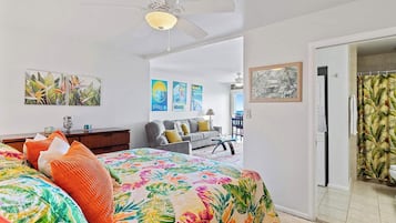 A bedroom with a bed, a ceiling fan, and a view of a balcony.