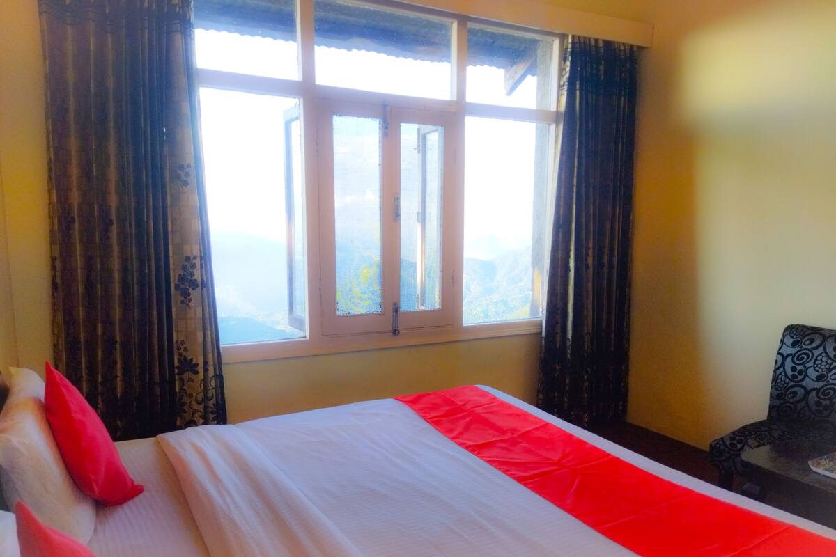 A hotel room with a bed, a chair, and a window with a view.