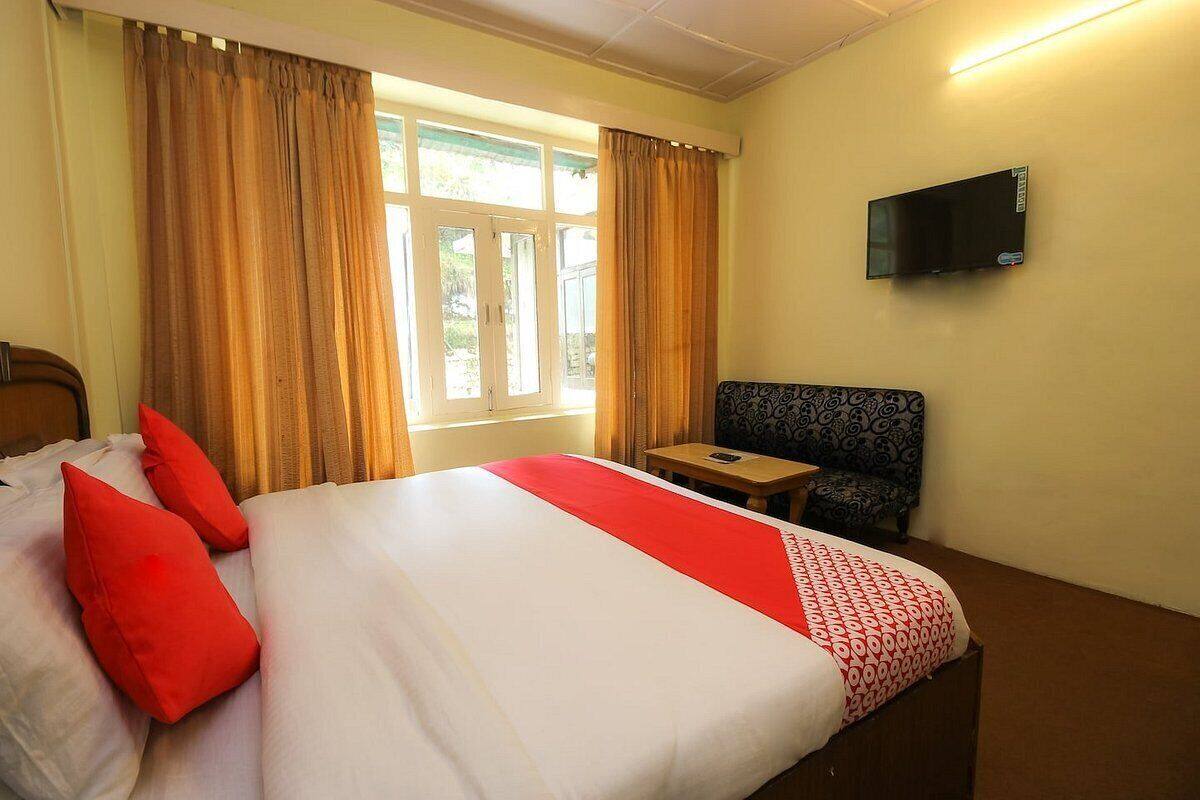 A hotel room with a bed, a TV, a small table, and a chair.