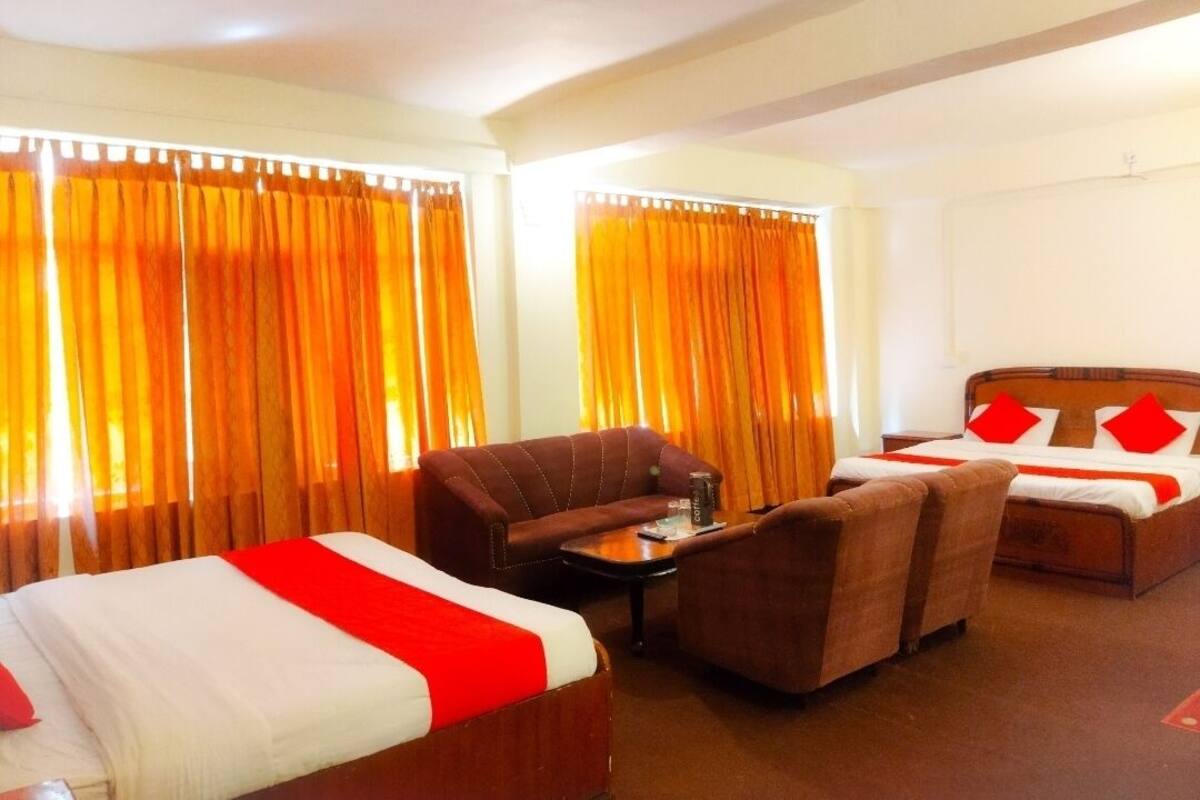 A hotel room with two beds, a sofa, a coffee table, and curtains.
