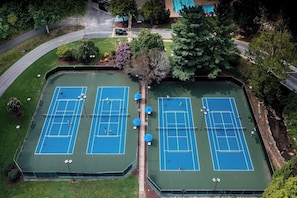 An aerial view of a tennis court complex with multiple courts, surrounded by trees and a road. - Apple Valley  52 at Rumbling Bald (Lake Lure)