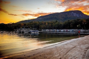 A waterfront dock with boats, a sandy beach, and a forested hill in the background. - Apple Valley  52 at Rumbling Bald (Lake Lure)