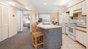 A compact kitchen with a central island, white cabinetry, and a microwave. - 2 bedroom 2 bath with outdoor pool, oceanblock - great prices! (Ocean City)