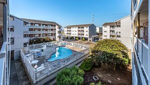 A multi-story residential building with a swimming pool, outdoor seating, and a well-maintained garden. - 2 bedroom 2 bath with outdoor pool, oceanblock - great prices! (Ocean City)