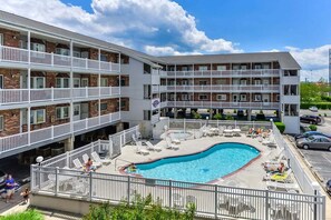 Un hotel a più piani con piscina e area salotto all'aperto.