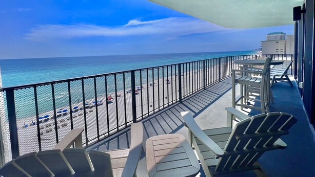 A balcony with a view of the beach and ocean, featuring Adirondack chairs and a table. - Beautiful Beachfront Condo, Free Beach Ser., Pool, Great Balcony Views! (panama city beach)