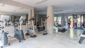Ein Fitnessstudio mit Trainingsgeräten, großen Spiegeln und einem sauberen, gefliesten Boden.