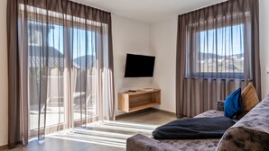 A modern living room with a flat-screen TV, a wooden console table, and a sofa with cushions.