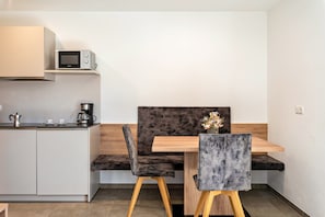 A modern kitchen with a microwave, coffee maker, and a bench.