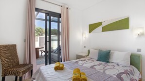 Une chambre d’hôtel avec un lit, une chaise, une table et une vue à travers une porte vitrée.