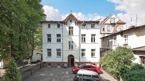 A multi-story building with a central entrance, a driveway, and parked cars. - Parkowa 33A2 - Beachfront Apartment with Parking by Lion Apartments Sopot (Sopot)