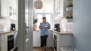 A modern kitchen with white cabinets, a coffee machine, and a potted plant. - Parkowa 33A2 - Beachfront Apartment with Parking by Lion Apartments Sopot (Sopot)
