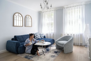 A living room with a blue sofa, a grey armchair, a small table, and a book.