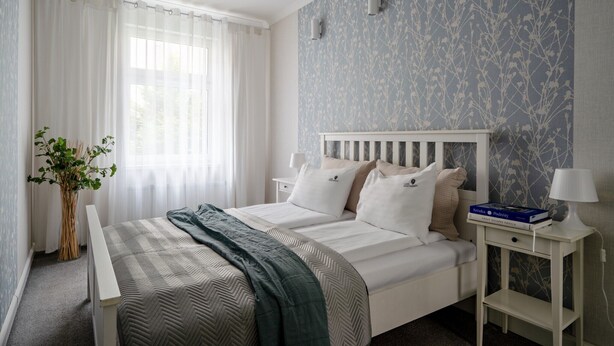 A bedroom with a bed, bedside tables, a lamp, a plant, and a window with curtains. - Parkowa 33A2 - Beachfront Apartment with Parking by Lion Apartments Sopot (Sopot)